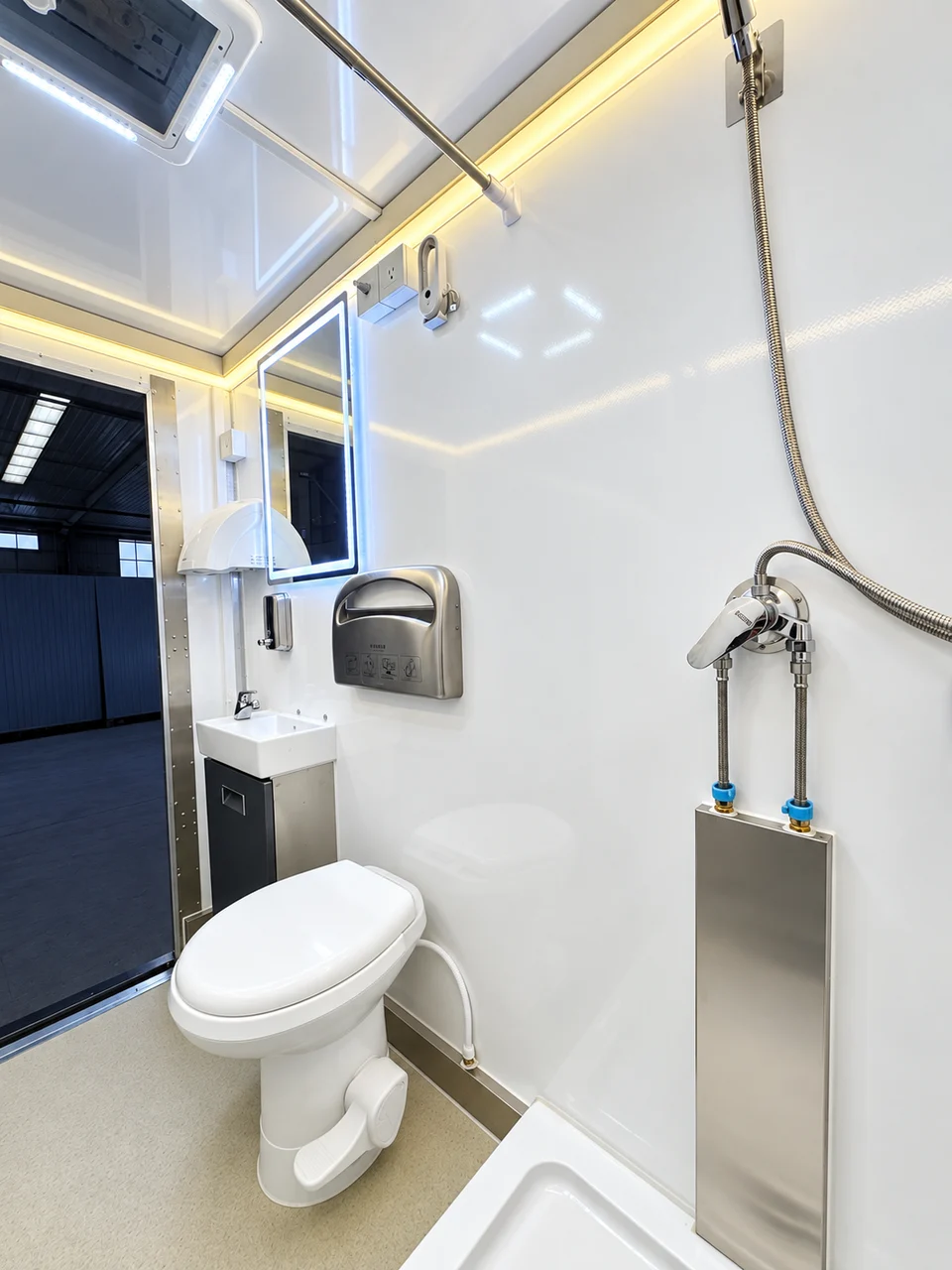 Standard shower-restroom trailer room with toilet, compact sink and handheld shower